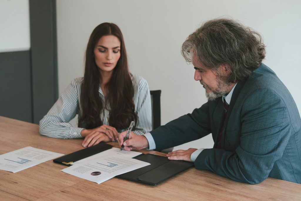 Professional business meeting with two colleagues reviewing documents at an office desk.